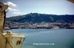 ID 2913 RANGITOTO (renamed ORIENTAL CARNAVAL) departing Wellington for UK.  The masts of ZLW Wellington Radio Station are visible on Tinakori Hill.  MAORI and HMNZS LACHLAN to be seen against the wharves.
